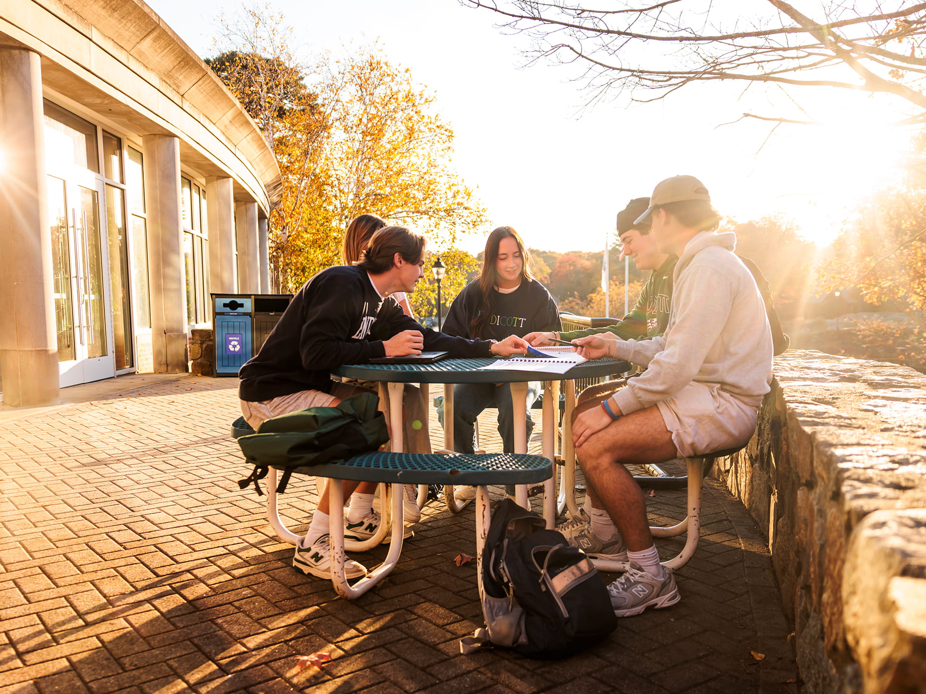 Students sitting at a picnic table socializing on the Endicott campus