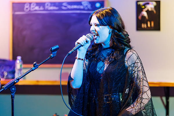 A vocalist sings into a handheld microphone during a live performance at Gully’s.