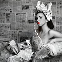 a woman sitting in a dressed made from newspapers