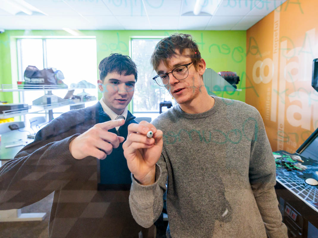 Students solving a problem on a glass surface