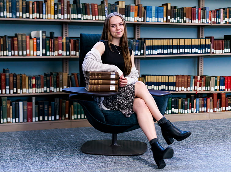 Student sitting in front of bookcase full of books
